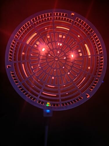 Rote Heizlampe mit Gittermuster leuchtet im Dunkeln.